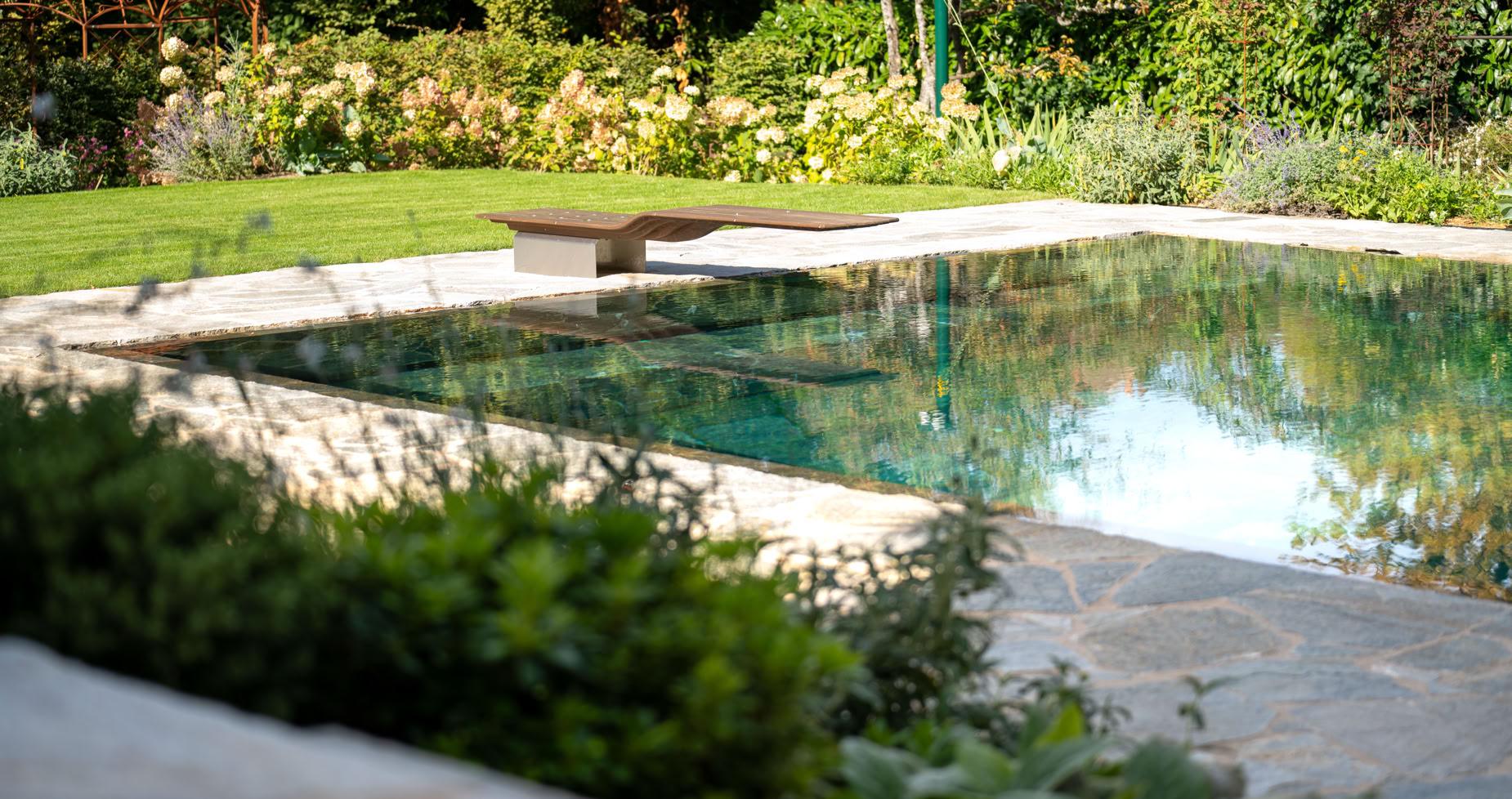 Piscine entourée de verdure avec des plantes et des arbres en arrière-plan à Collonge-Bellerive.