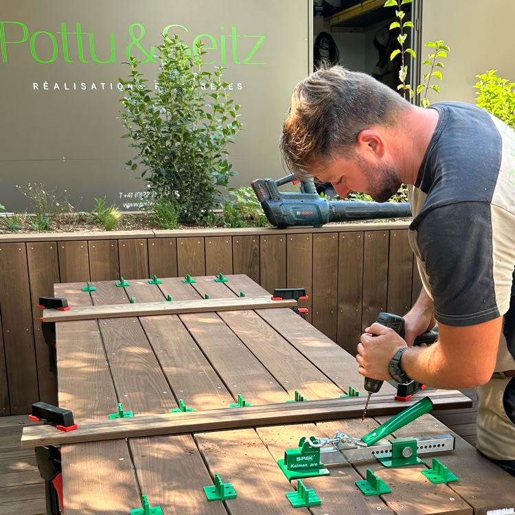 Jardin avec pelouse verte, arbustes, arbres et allée en pierre à Collonge-Bellerive.