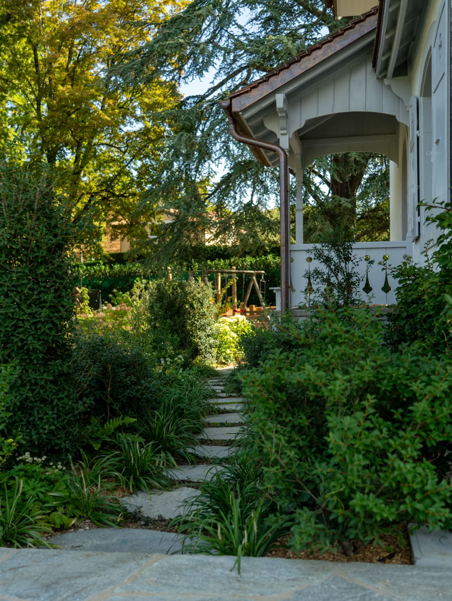 Chemin en pierre menant à une maison entourée de verdure et d'arbres à Collonge-Bellerive.