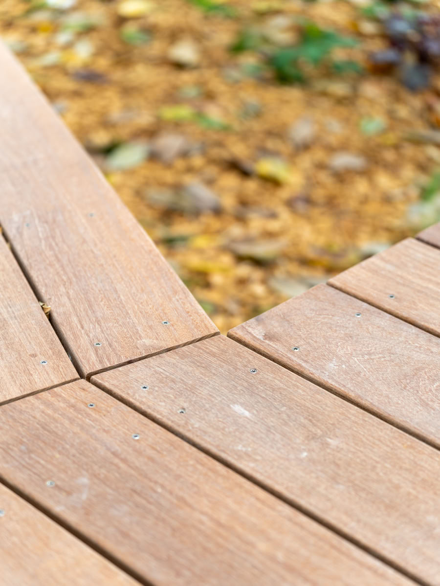Terrasse en bois avec des feuilles mortes floues en arrière-plan.